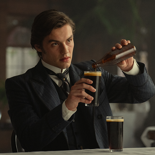 Edward Guinness (Louis Partridge) demonstrating how to pour Guinness